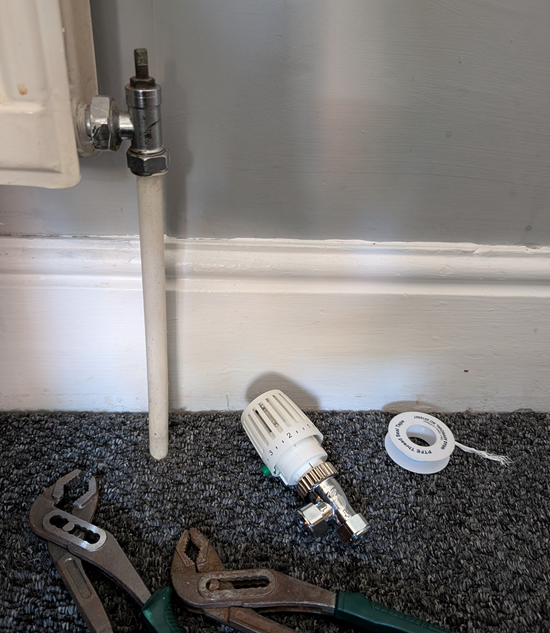 New white thermostatic radiator valve replacement installed on a traditional radiator in a York town house